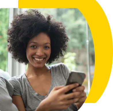 Foto de uma mulher sorrindo enquanto olha o celular.