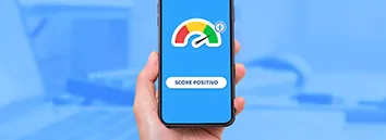 Mão segurando um celular com o ponteiro do medidor de score no verde.