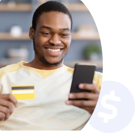 Homem sorrindo com o cartão de crédito em uma mão e o celular na outra.
